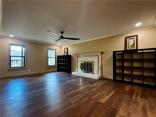 a view of an empty room with wooden floor fireplace and a window