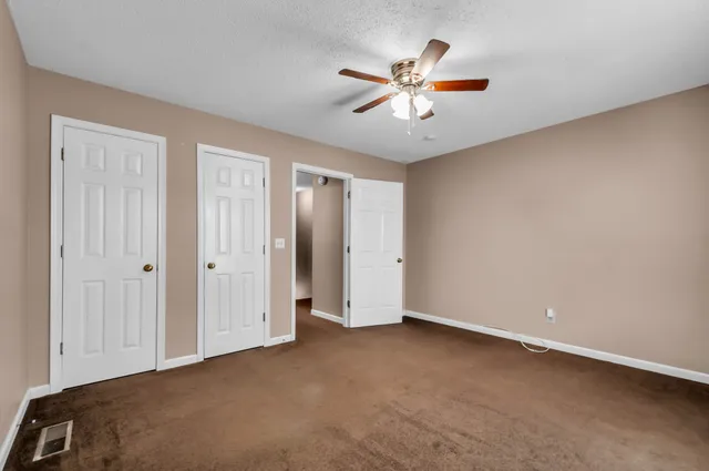 a view of an empty room with chandelier fan