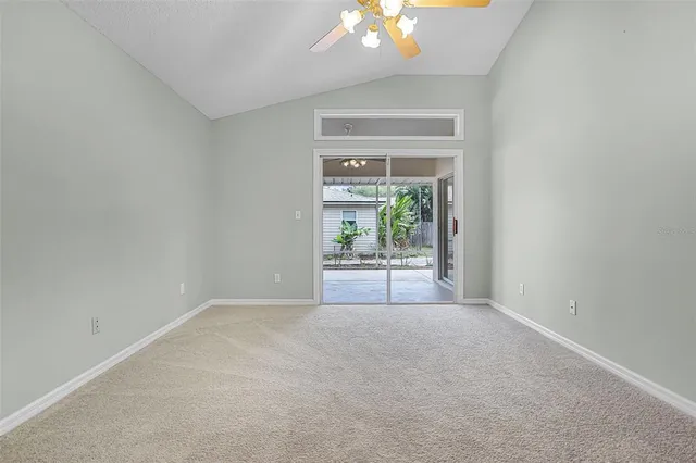 an empty room with chandelier fan and windows