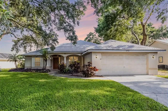 a front view of a house with a garden and trees