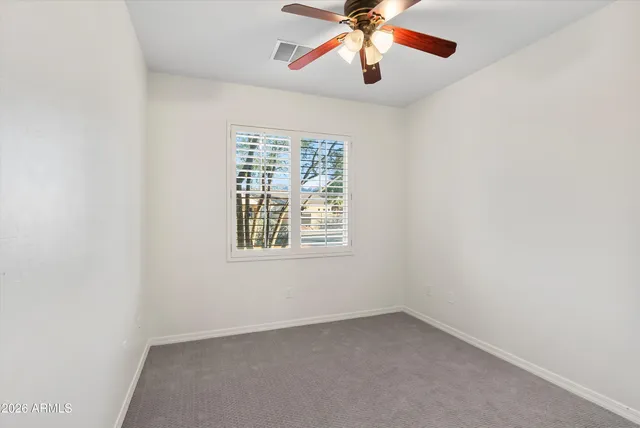 an empty room with a window and a fan