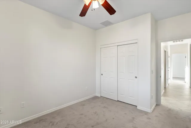 an empty room with a ceiling fan and carpet