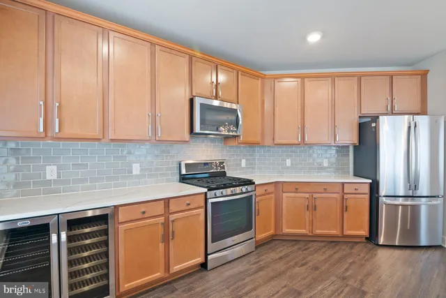 a large kitchen with stainless steel appliances granite countertop a refrigerator a sink dishwasher and wooden cabinets with wooden floor