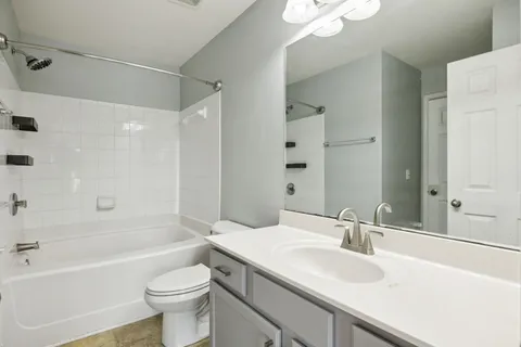 a bathroom with a sink a toilet a mirror a bathtub and shower