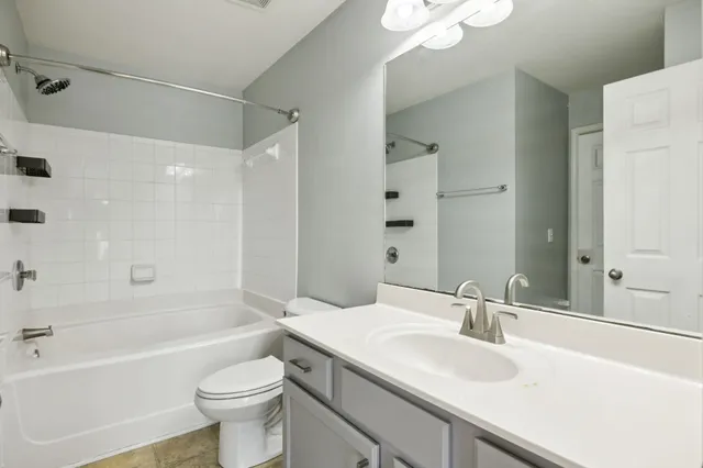 a bathroom with a sink a toilet a mirror a bathtub and shower