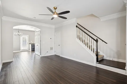 a view of an empty room with wooden floor and a ceiling fan