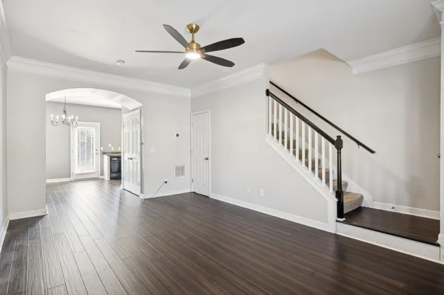 a view of an empty room with wooden floor and a ceiling fan