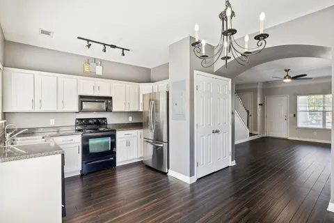 a kitchen with stainless steel appliances kitchen island granite countertop a wooden floors and white cabinets