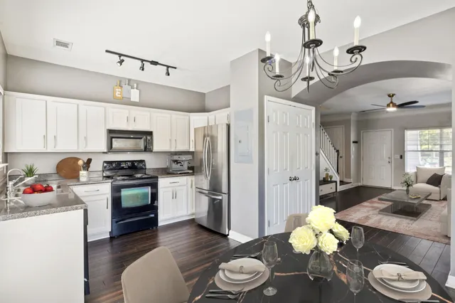 a kitchen with stainless steel appliances kitchen island granite countertop a refrigerator a stove a sink dishwasher and white cabinets with wooden floor