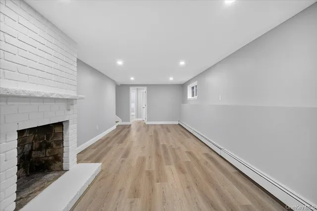 a view of empty room with wooden floor and fireplace
