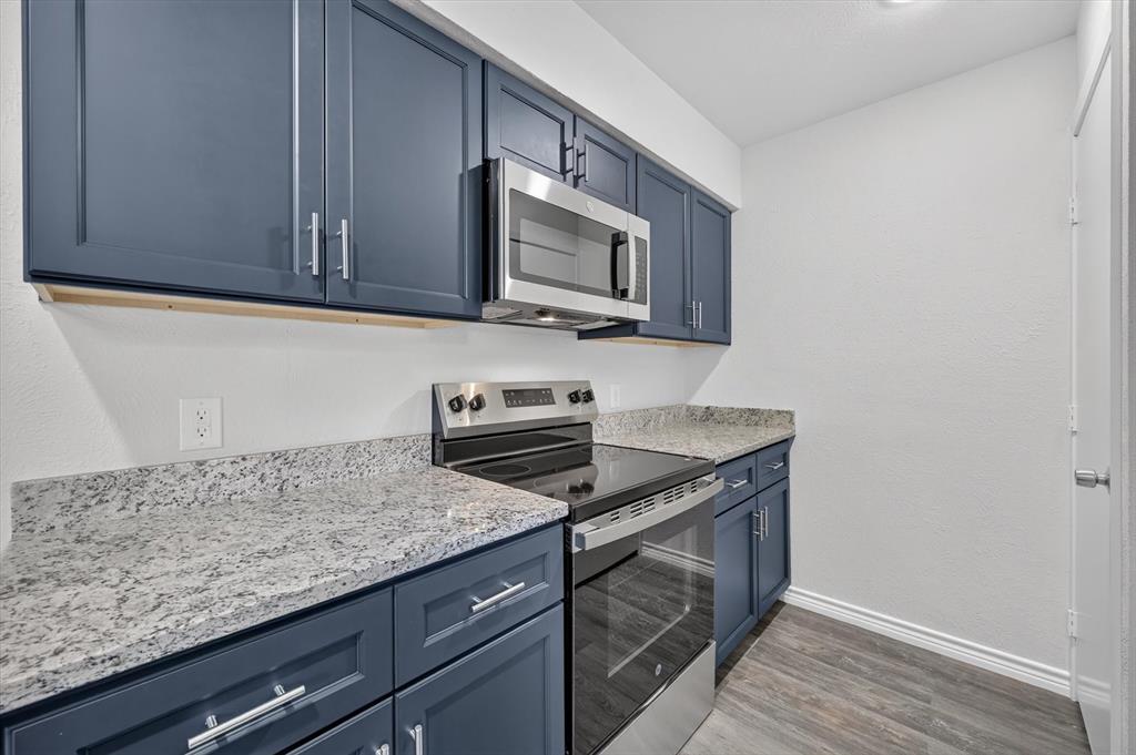 1801 East Grauwyler Road, Unit 101 Irving, TX 75061 - Photo 11 of 39 a kitchen with granite countertop cabinets stainless steel appliances and wooden floor