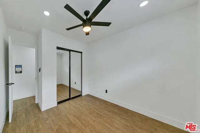 an empty room with wooden floor and a ceiling fan
