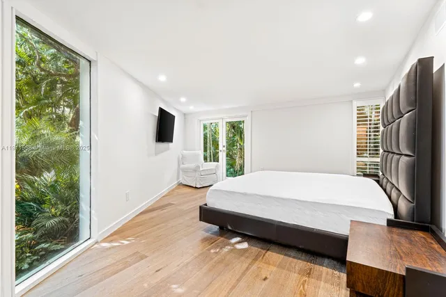 a bedroom with a bed window and a flat tv screen