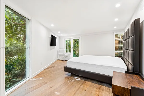 a bedroom with a bed window and a flat tv screen