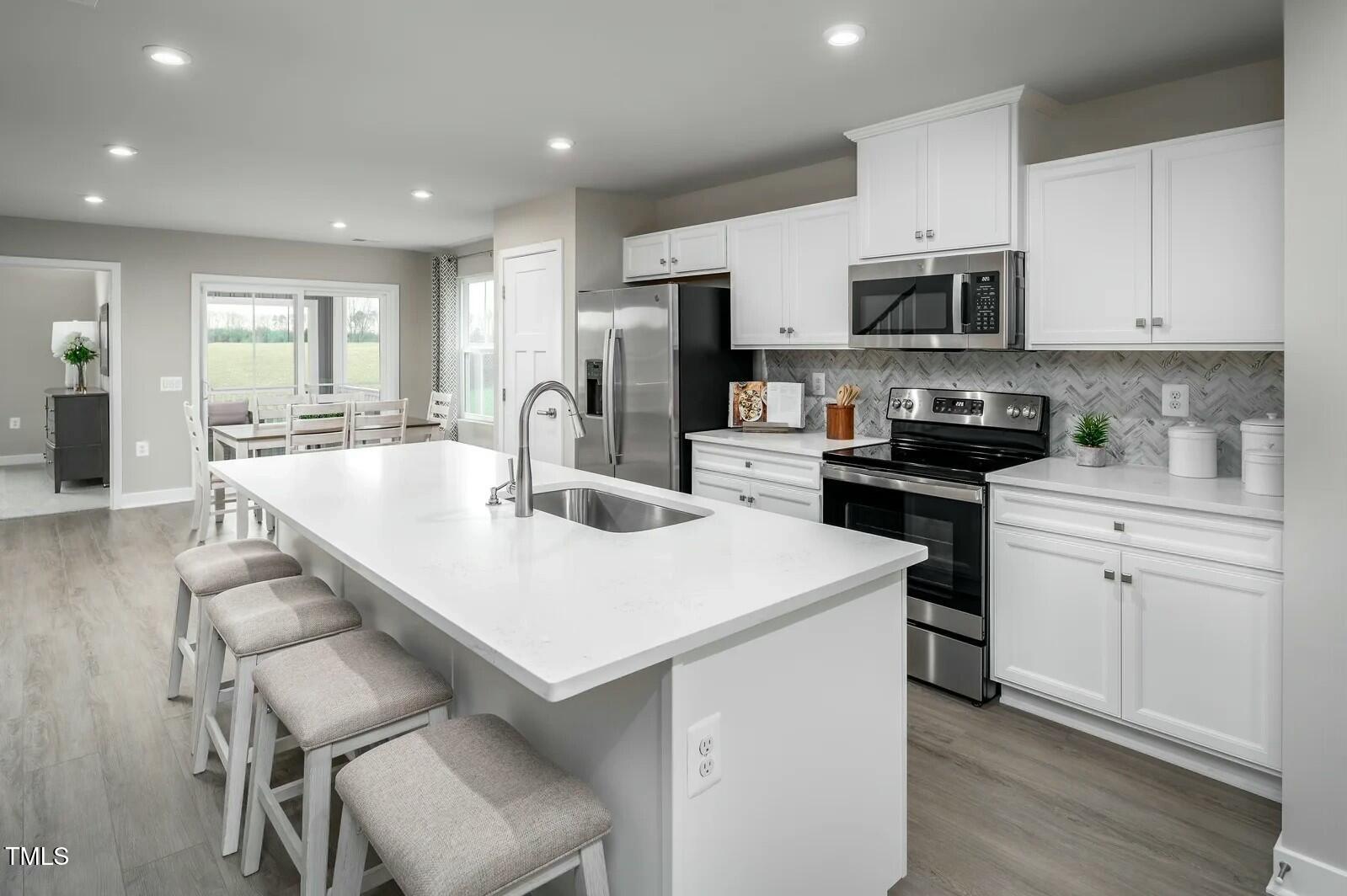 460 Grand Silo Road Raleigh, NC 27603 - Photo 2 of 12 a kitchen with stainless steel appliances a white table chairs and a refrigerator