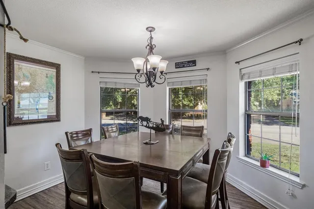a dining room with wooden floor a chandelier a wooden table and chairs