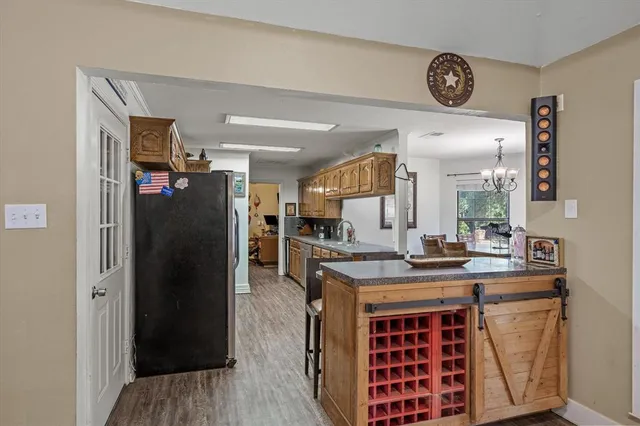 a kitchen with stainless steel appliances granite countertop a refrigerator a stove and a sink with wooden floor