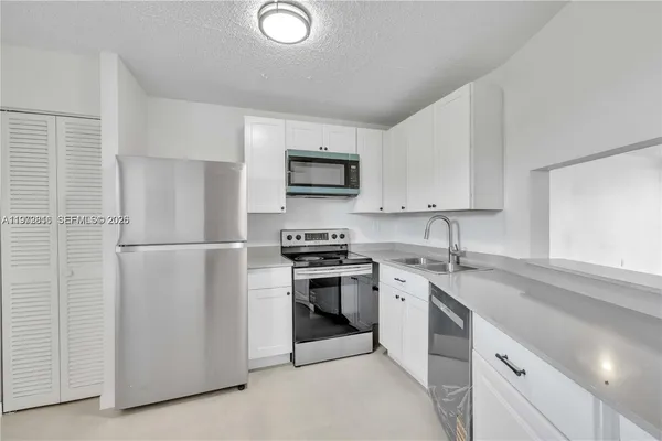 a kitchen with stainless steel appliances granite countertop white cabinets a microwave a sink and a refrigerator