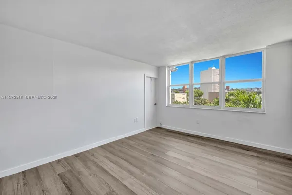 a view of an empty room with a window and wooden floor