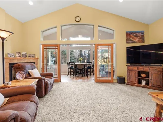 a living room with furniture a flat screen tv and floor to ceiling window