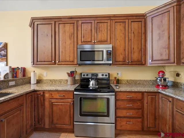 a kitchen with granite countertop a stove top oven microwave and cabinets