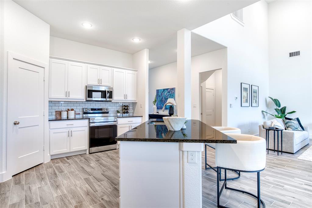 229 Cisco Trail Forney, TX 75126 - Photo 9 of 27 a kitchen with kitchen island granite countertop a stove cabinets and wooden floor