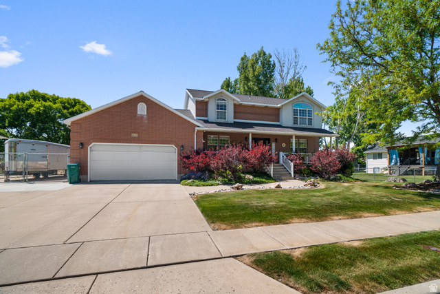 5727 South 3550th Street West Roy, UT 84067 - Photo 2 of 49 Two-story residence featuring a brick facade with a columned front porch and a two-car garage