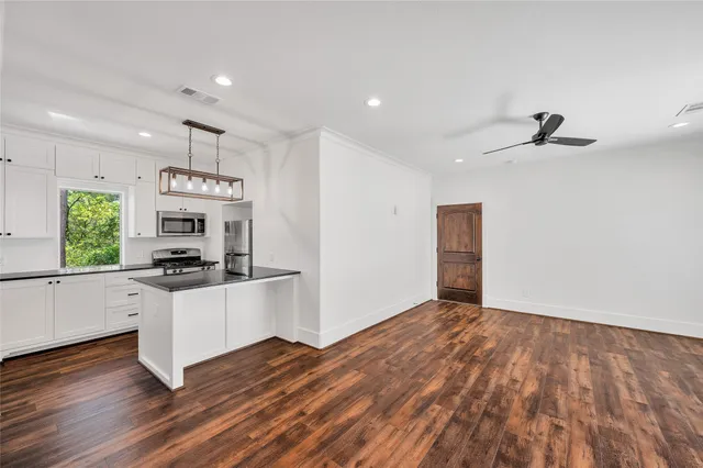 a kitchen with granite countertop a stove a sink and a refrigerator