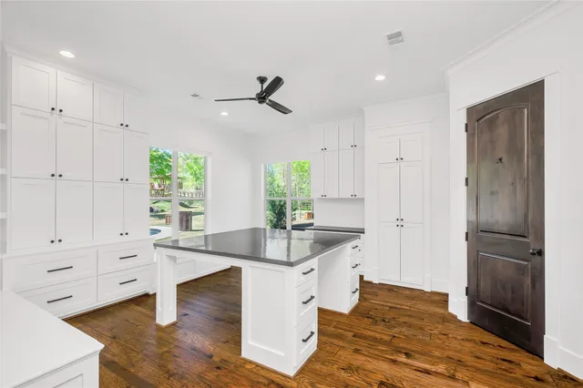 a living room with kitchen island white cabinets and wooden floor