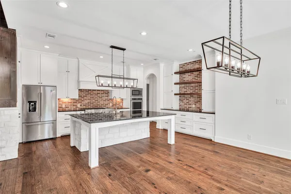 a kitchen with stainless steel appliances granite countertop a refrigerator a stove and a wooden floors