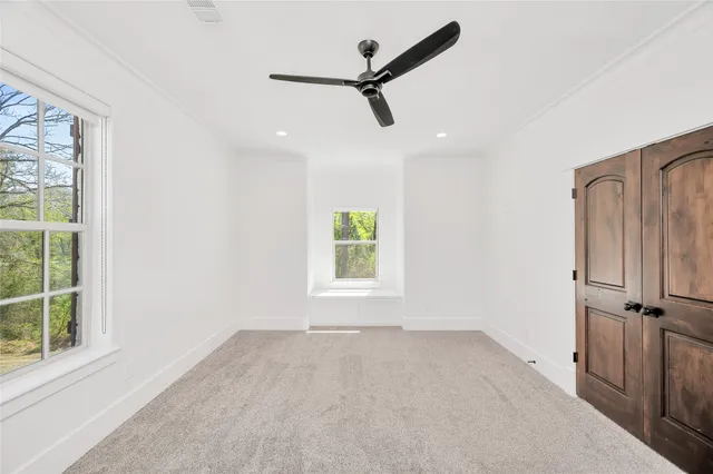 an empty room with windows and a ceiling fan