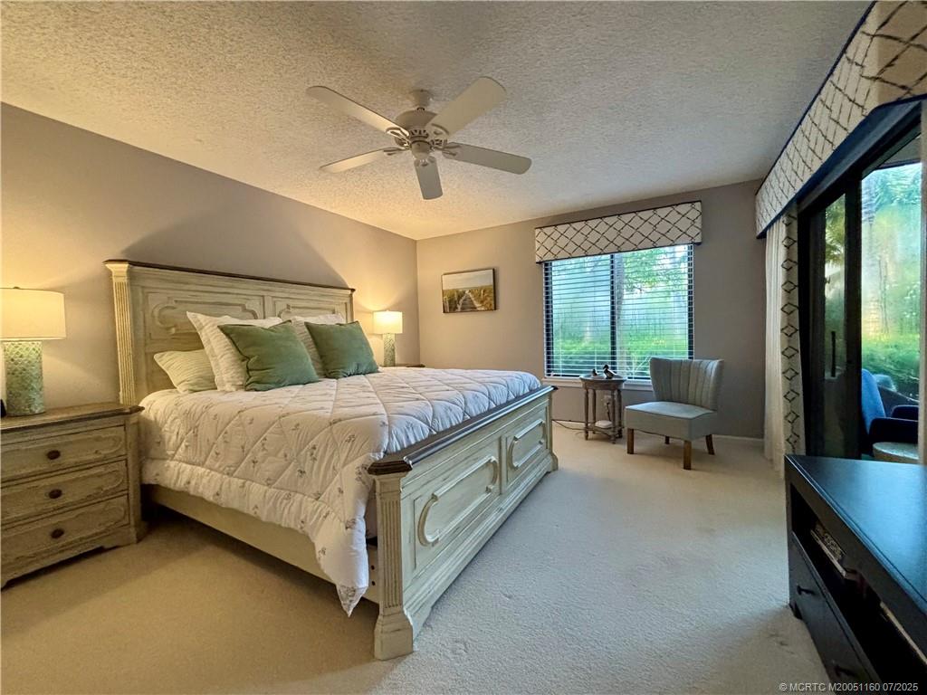 5152 Southeast Club Way, Unit 104 Stuart, FL 34997 - Photo 15 of 28 a bedroom with a bed and large windows
