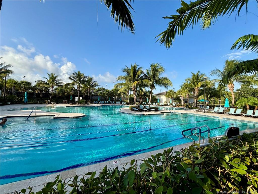 5152 Southeast Club Way, Unit 104 Stuart, FL 34997 - Photo 22 of 28 a view of swimming pool with a yard and palm trees