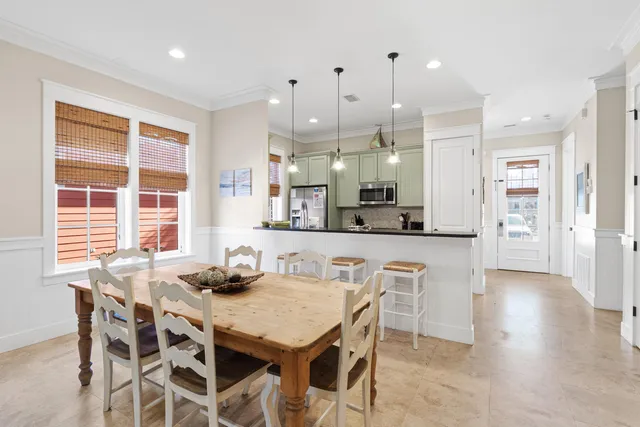 a kitchen with stainless steel appliances kitchen island granite countertop a dining table chairs and white cabinets