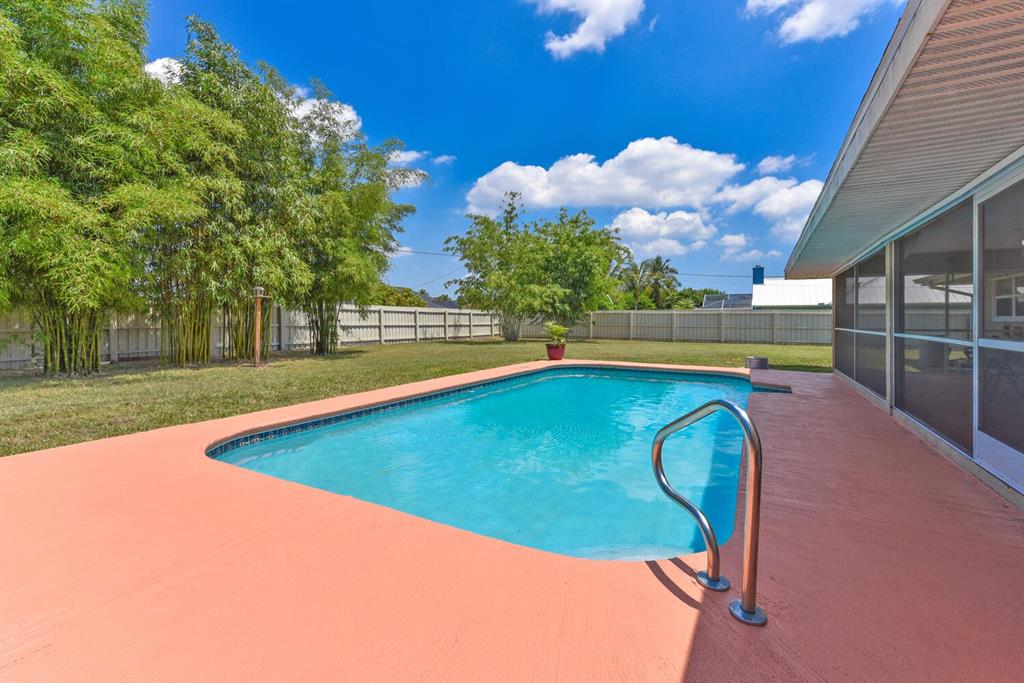 2962 Southeast Darien Road Port St. Lucie, FL 34952 - Photo 26 of 33 a view of a swimming pool with a bench and trees in the background