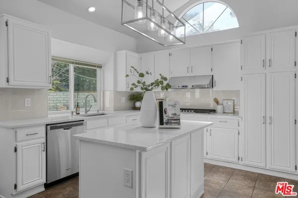 a kitchen with white cabinets and chandelier