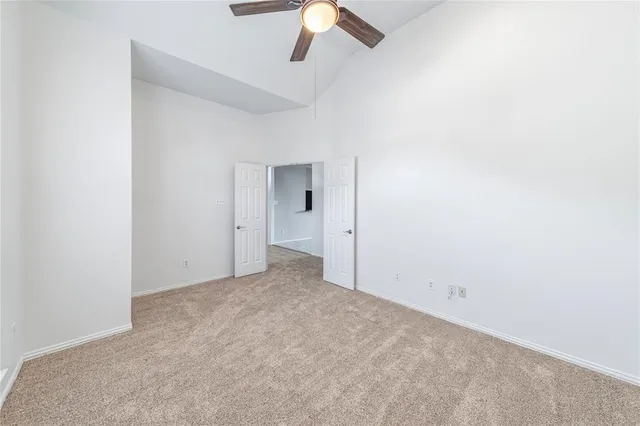 an empty room with a fan & a ceiling fan