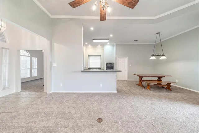 an empty room with kitchen and view of a living room