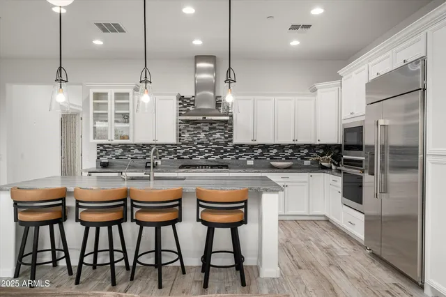 a kitchen with stainless steel appliances kitchen island granite countertop a table chairs sink and cabinets