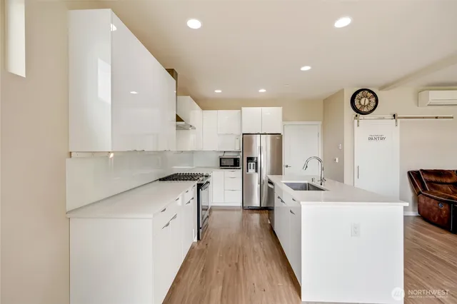 a kitchen with a sink a stove oven a refrigerator with white cabinets and wooden floor