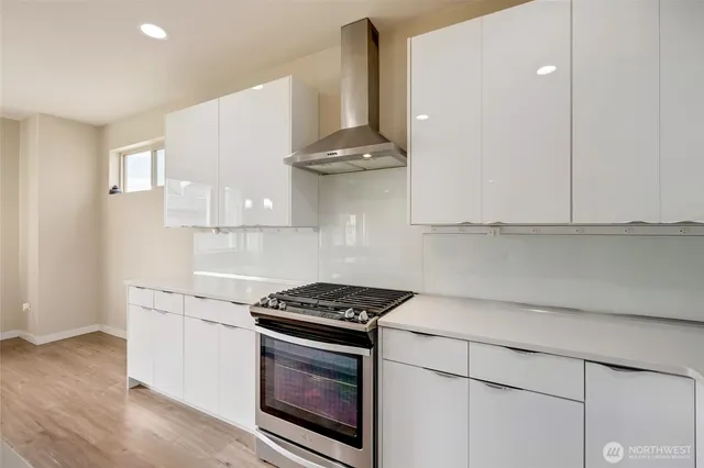 a kitchen with stainless steel appliances a stove a white cabinet and a granite counter tops