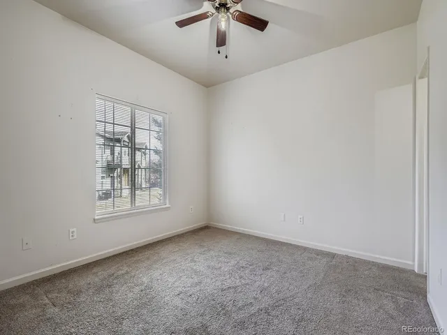 an empty room with windows and ceiling fan