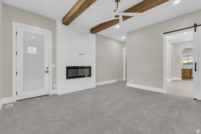 2828 Jojo Road Eagle Mountain, UT 84005 - Photo 24 of 63 Spacious room featuring vaulted ceilings with exposed wood beams, a contemporary linear fireplace set into a white brick wall, and plush gray carpeting