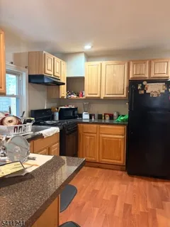 a kitchen with granite countertop a refrigerator stove sink and cabinets