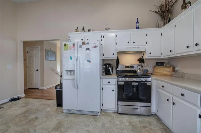 a kitchen with granite countertop white cabinets and refrigerator