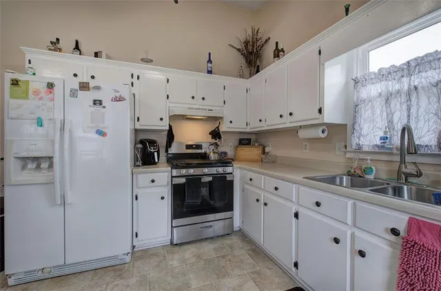 a kitchen with granite countertop white cabinets and refrigerator