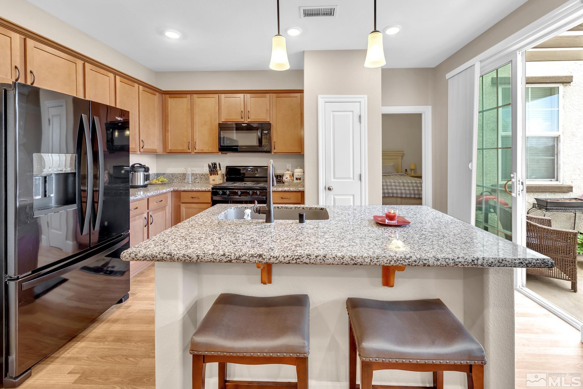 1880 Dark Horse Road, Unit A Reno, NV 89521 - Photo 5 of 20 a kitchen with granite countertop kitchen island stainless steel appliances a sink refrigerator and microwave