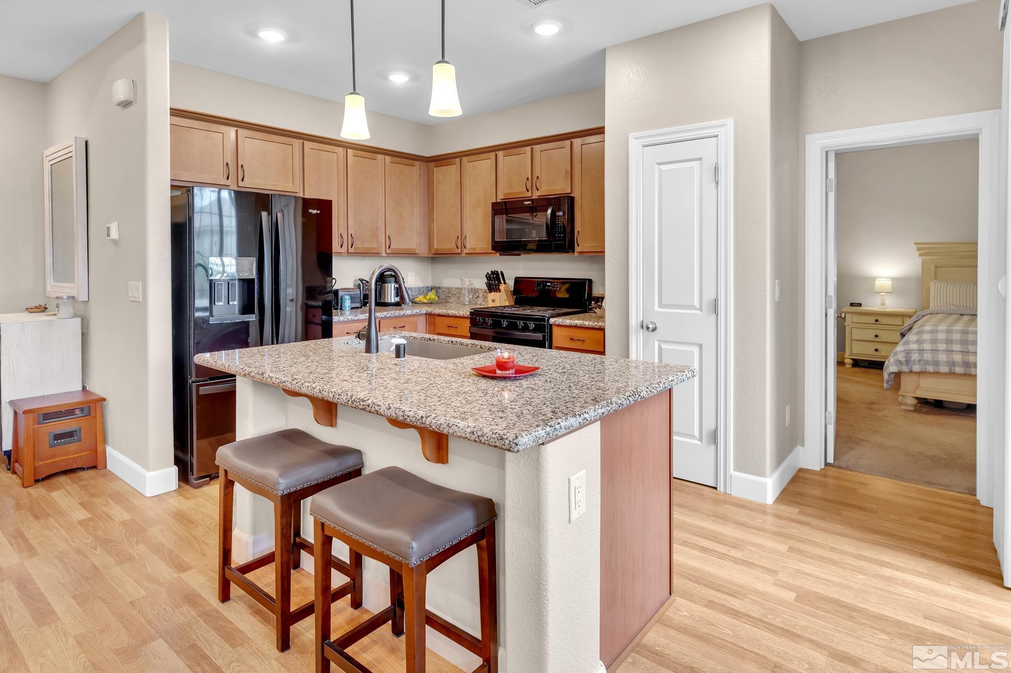 1880 Dark Horse Road, Unit A Reno, NV 89521 - Photo 6 of 20 a kitchen with granite countertop kitchen island stainless steel appliances a refrigerator oven a sink a dining table and chairs with wooden floor