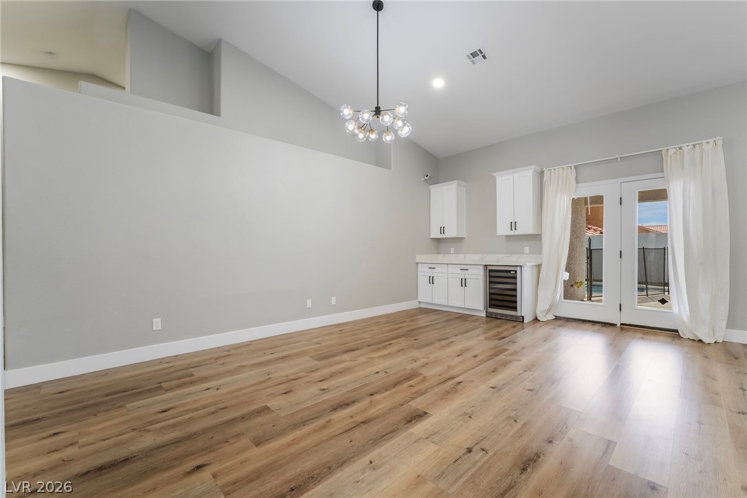 9171 West Viking Road Las Vegas, NV 89147 - Photo 12 of 43 Hardwood-style flooring and soaring ceilings characterize this versatile living area with a convenient wet bar and direct patio access.