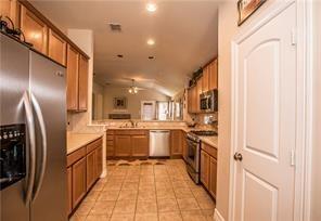 1409 Rosson Road Little Elm, TX 75068 - Photo 25 of 34 Kitchen featuring wood cabinetry, stainless steel appliances, and tile flooring